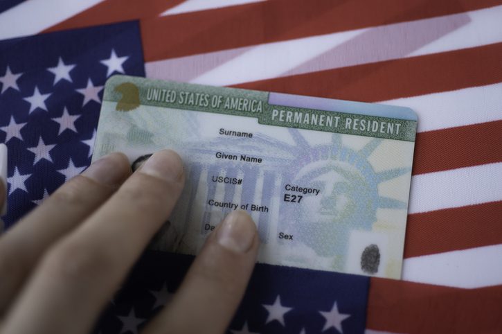 Permanent Resident Green card  of United states of America on flag of USA. Above close up view.